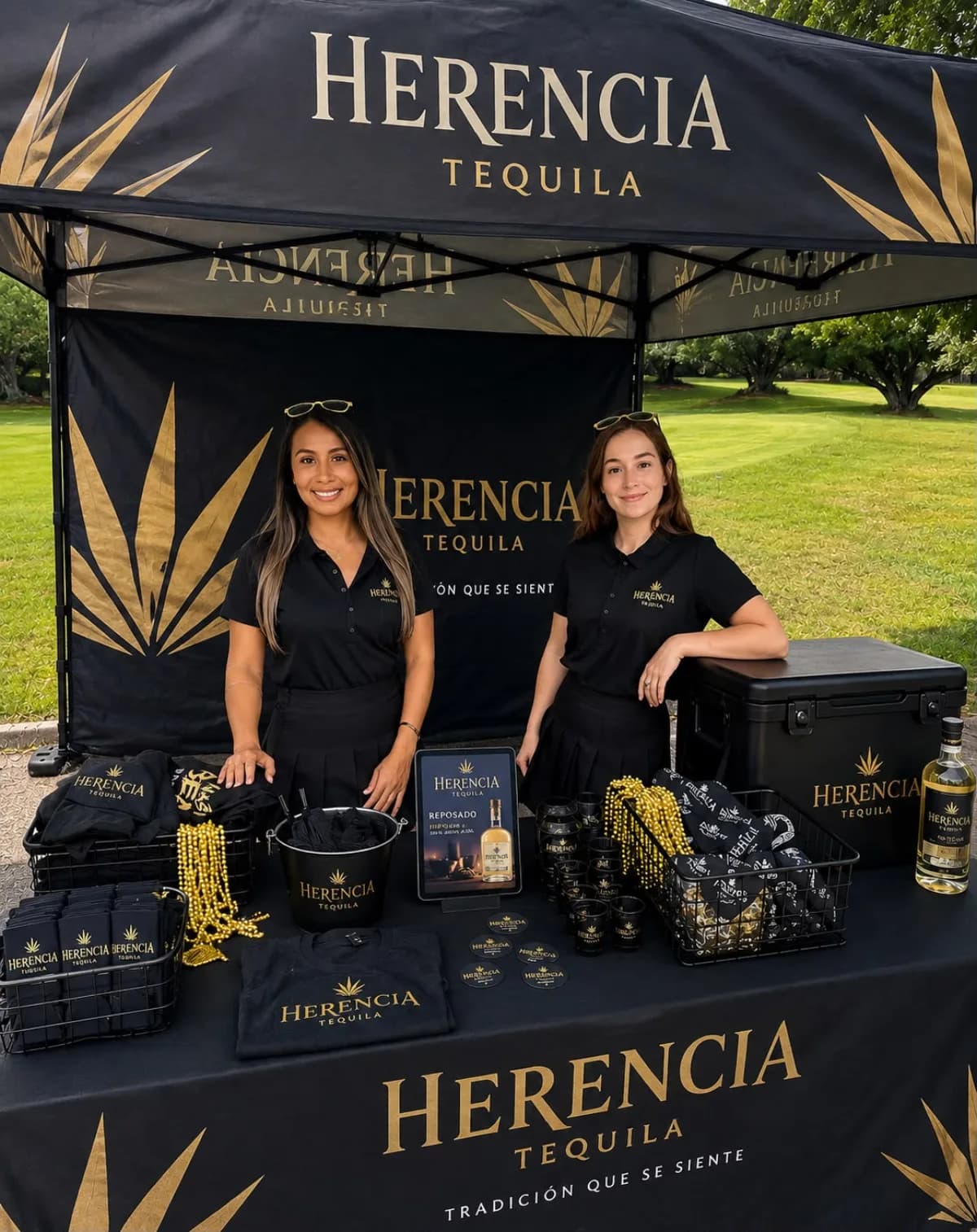 Two bilingual ambassadors at a premium tequila tasting booth — a branded tasting kit, sampling setup and bottle display at an outdoor activation.